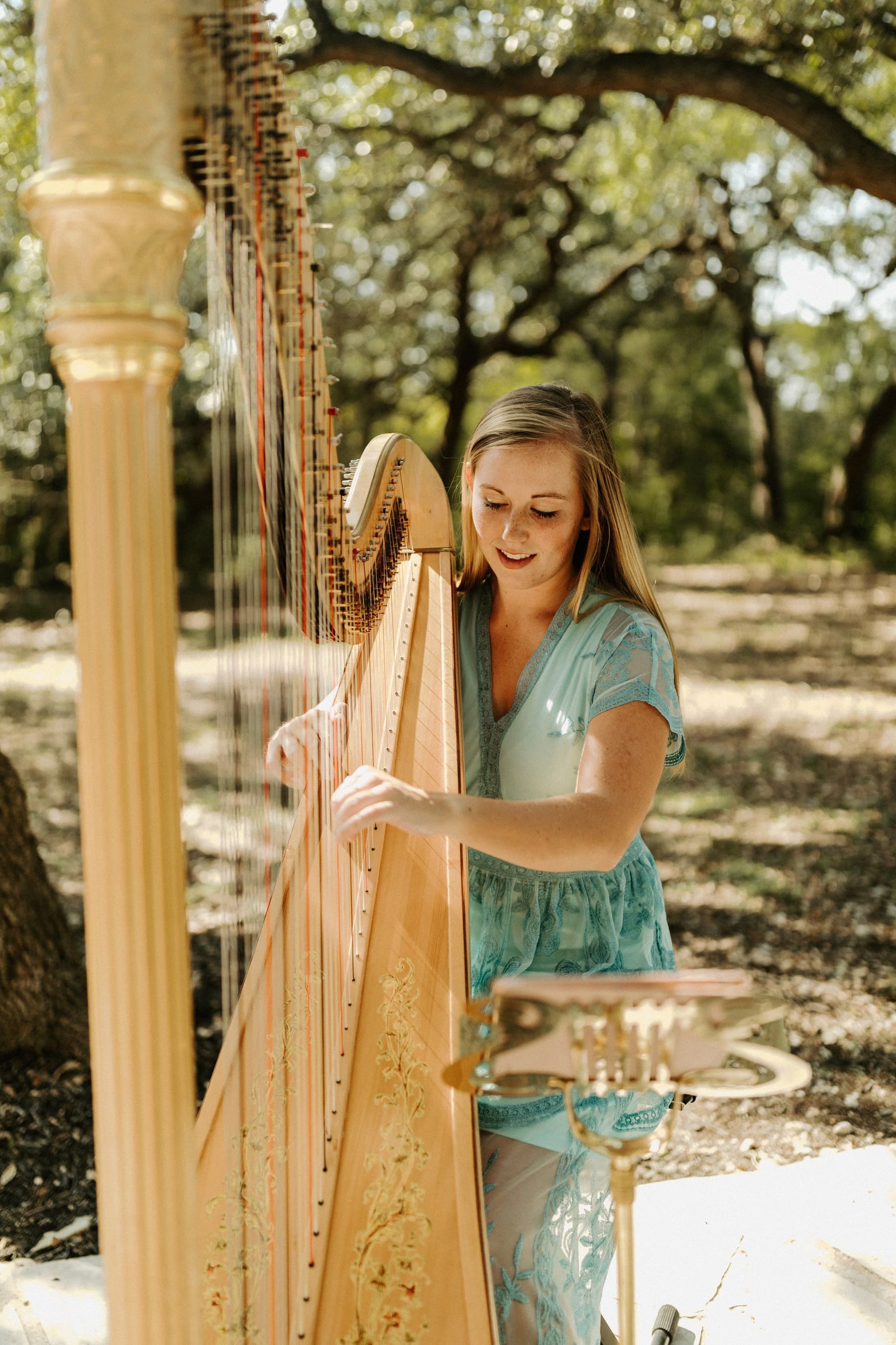 Grace Neal Dudney playing harp at an outdoor wedding ceremony