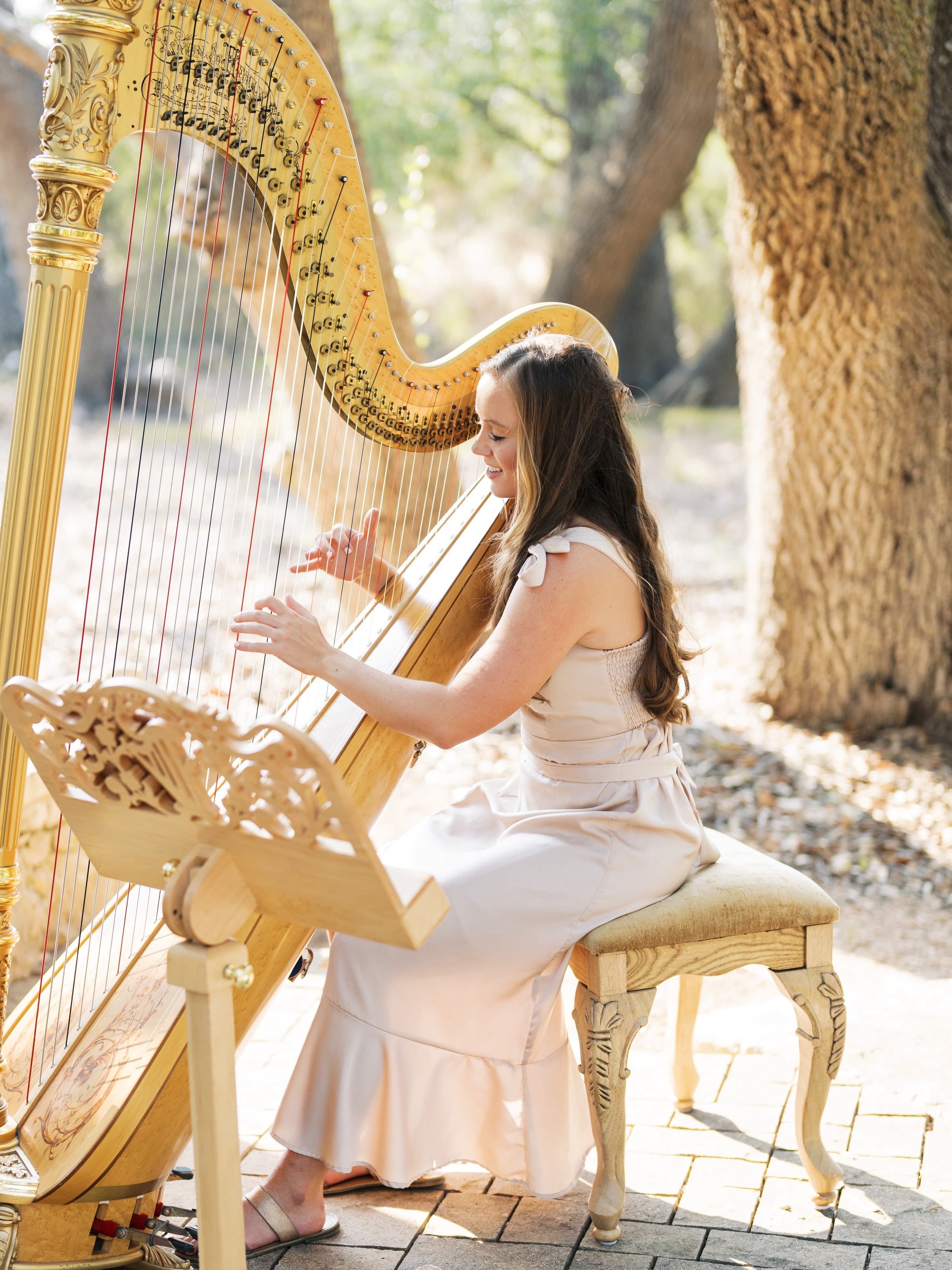 Grace Neal Dudney playing a gold concert harp outdoors
